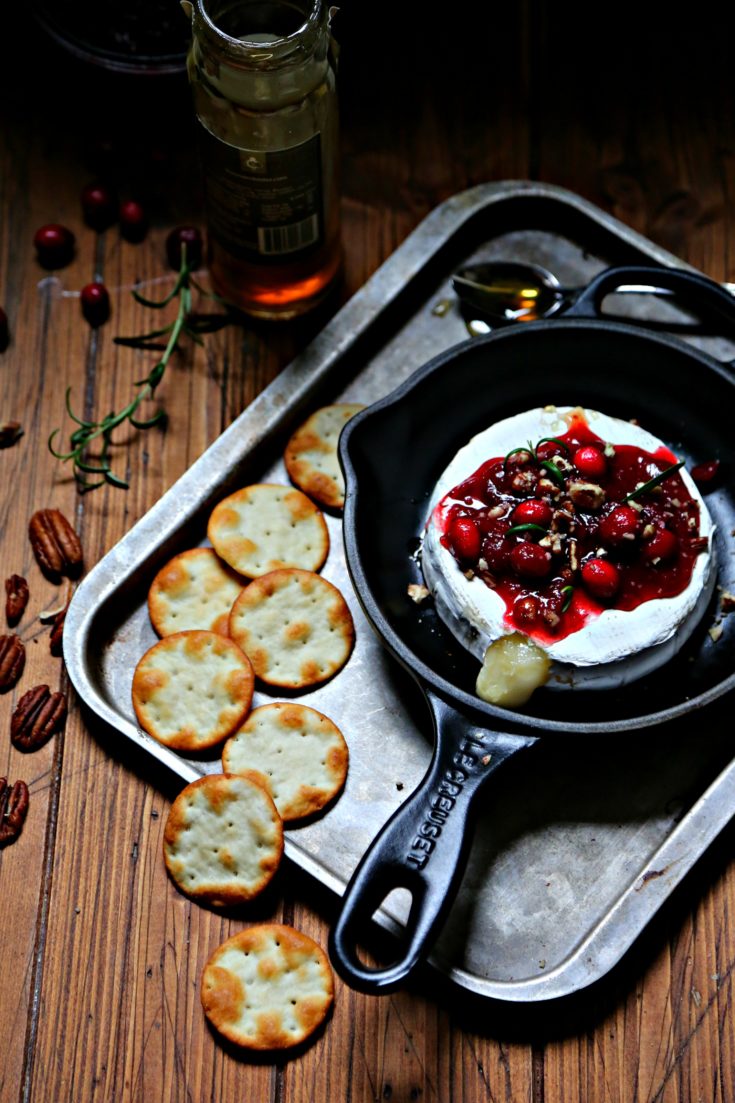 Cranberry Pecan Baked Brie in cast iron skillet surrounded by crackers