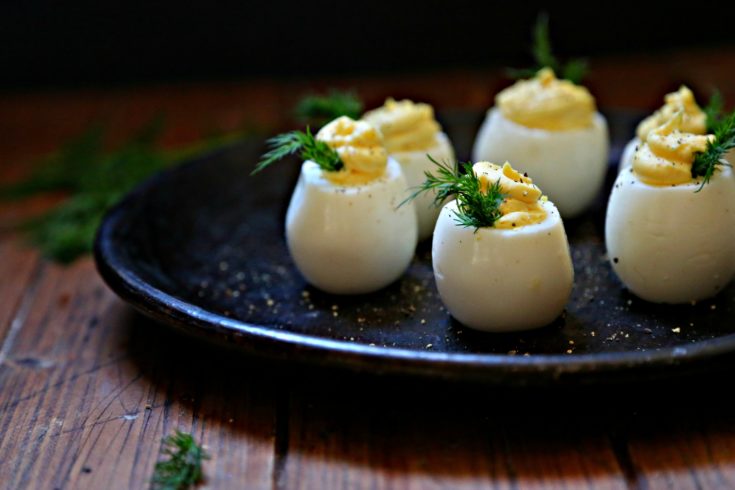 Deviled Eggs on brown plate garnished with dill