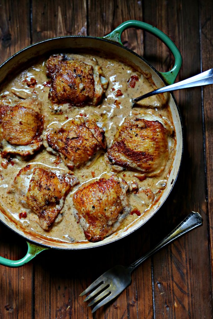 Chicken Thighs with Creamy Garlic Mushroom Sauce ub green skillet with spoon in sauce