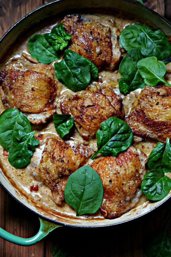 Chicken Thighs with Creamy Garlic Mushroom Sauce with spinach in green skillet