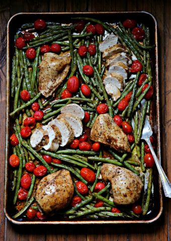 Chicken, Green Beans and Roma Tomatoes on a sheet pan. Serving fork under green beans.
