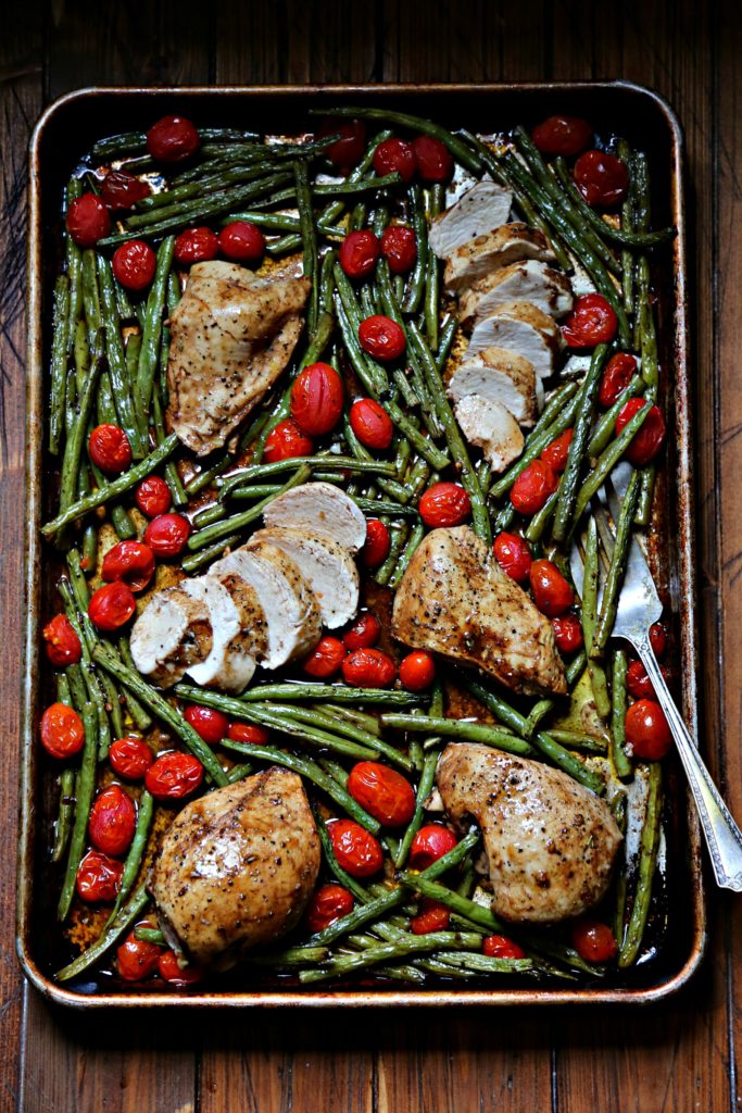 Chicken, Green Beans and Roma Tomatoes on a sheet pan. Serving fork under green beans.