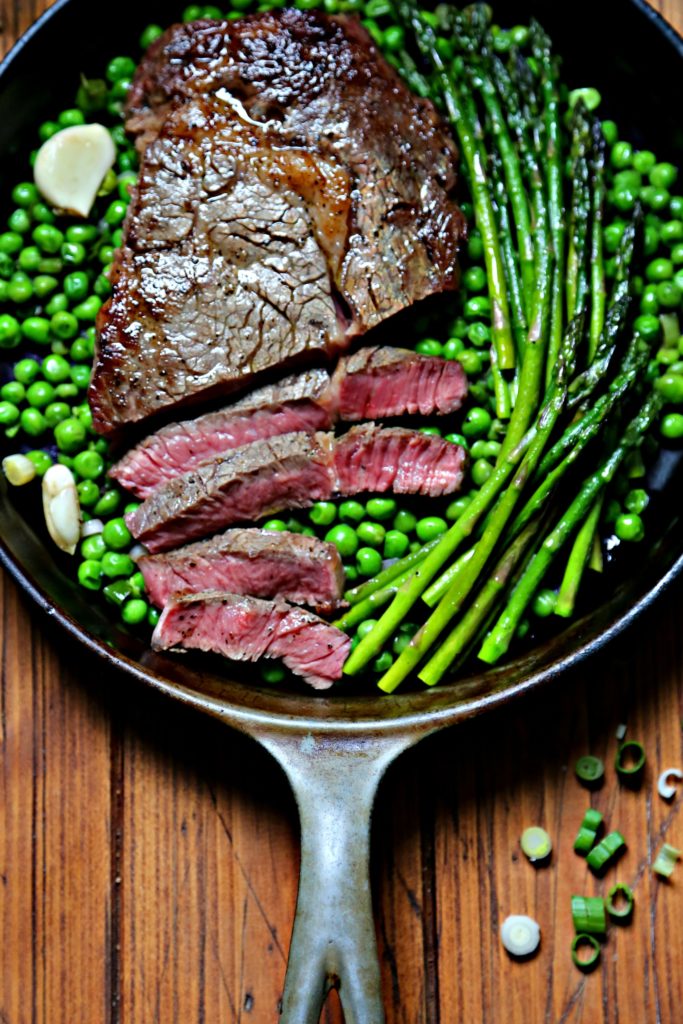 Cast iron skillet with spirng peas, asparagus and steak. 