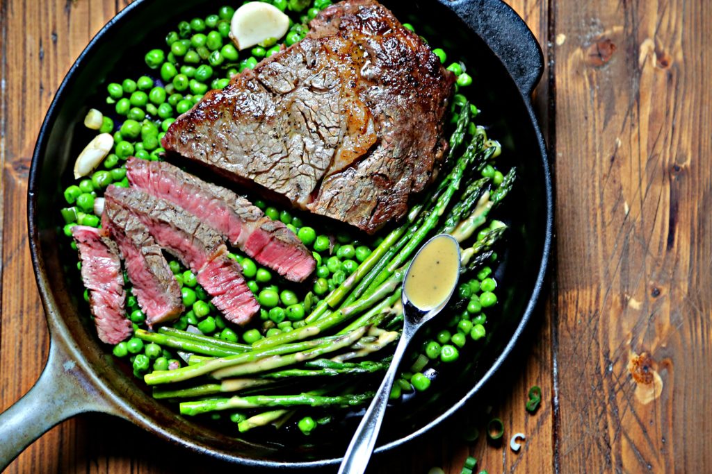Cast iron skillet with spring peas, asparagus and steak. 