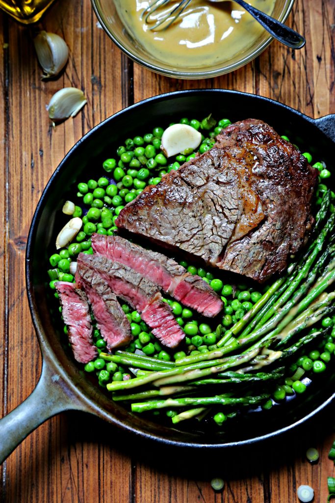 Cast iron skillet with spring peas, asparagus and steak.