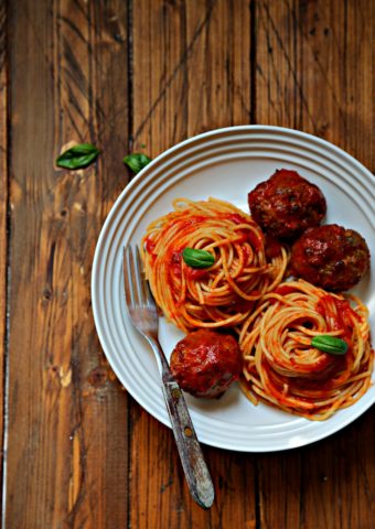 spaghetti and meatballs in white bowl with fork.