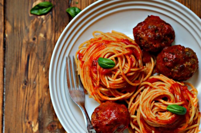 spaghetti and meatballs in white bowl with fork.