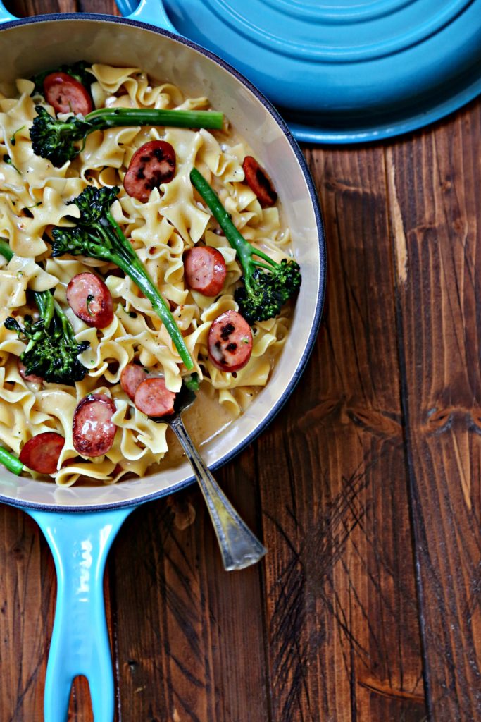 Pasta with sausage and broccoli in blue pan.