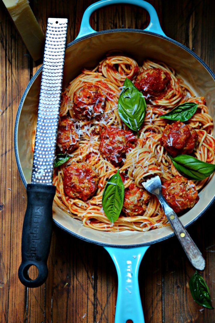 Spaghetti and Meatballs with basil in blue pot. Microplane to side.