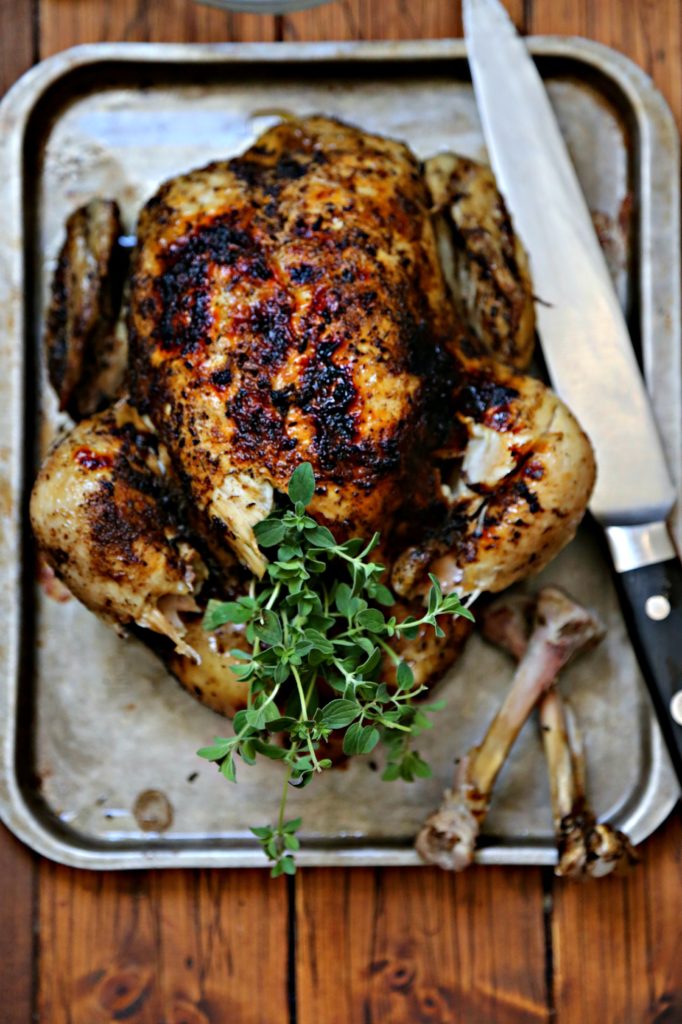 Whole roasted chicken on baking sheet with knife. 