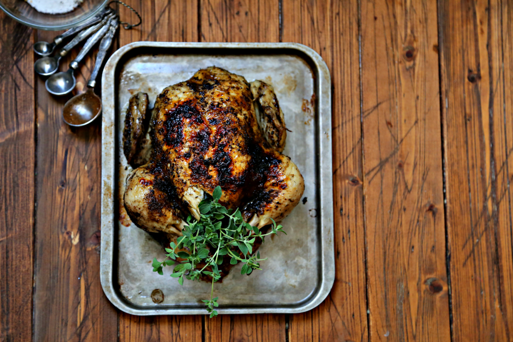 Whole roasted chicken on baking sheet. Fresh Thyme in chicken.