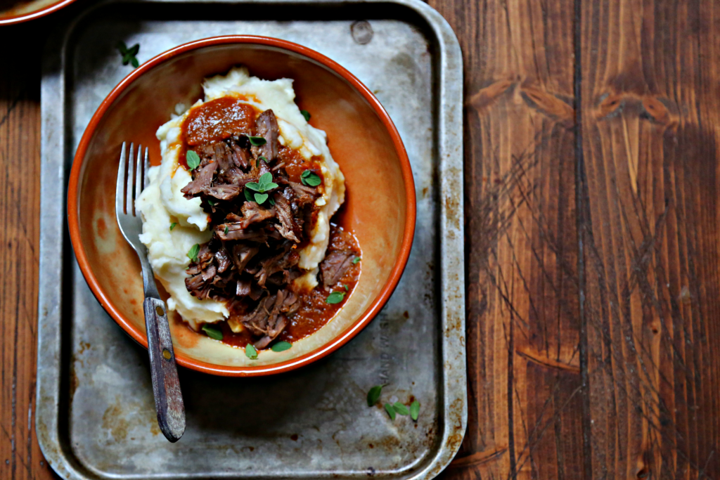 Coca Cola Braised Short Ribs in brown bowl served over mashed potatoes. 