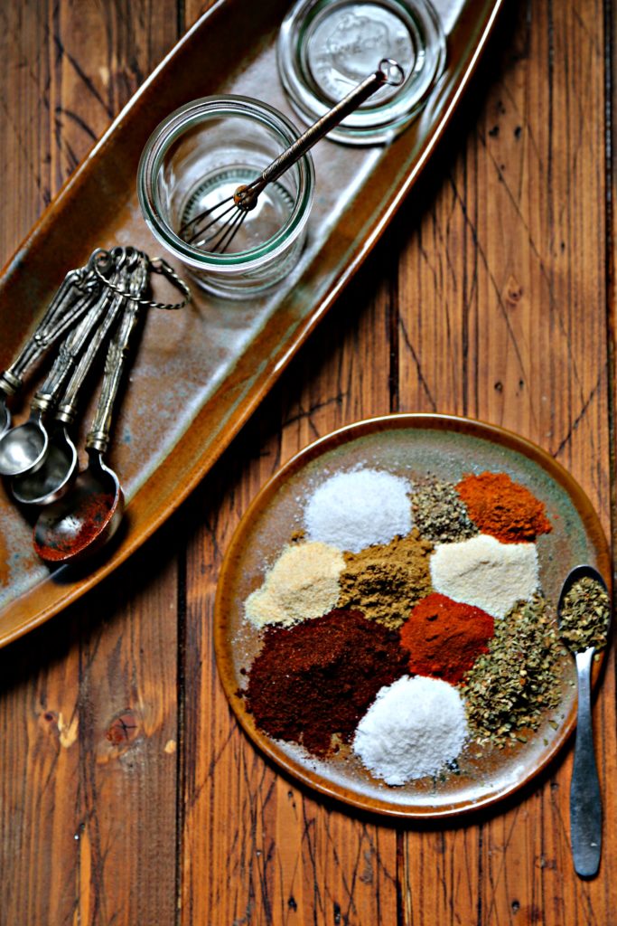 Spices to make fajita seasoning on brown plate with spoon.