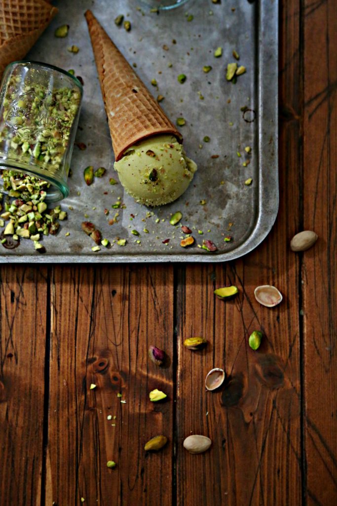 baking sheet with pistachio ice cream cone on its side. Small glass jar of pistachios on its side. 