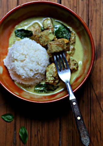 Brown bowl with rice ball, and thai basil curry chicken. Fork in piece of chicken.