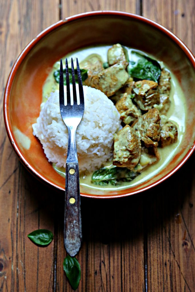 Brown bowl with rice ball coconut curry chicken. Fork placed on rice.