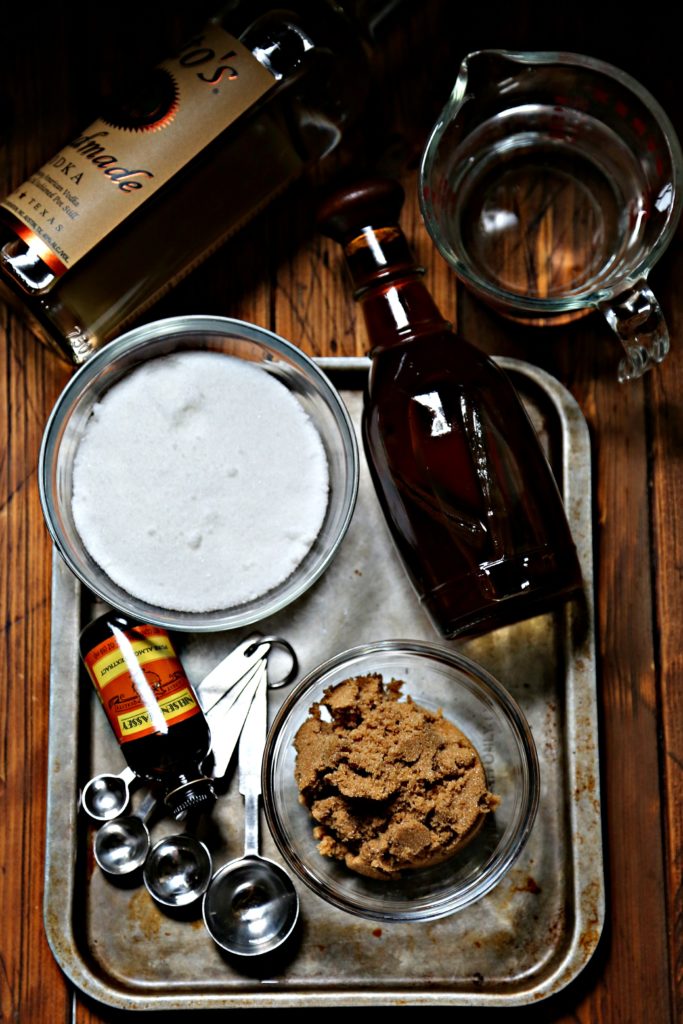 Glass Bottle with stopper of homemade amaretto with small white bowl of brown sugar in background via Bell'Alimento