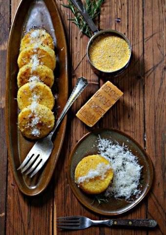 Polenta Cakes on brown platter with cheese and wood background via bell'alimento