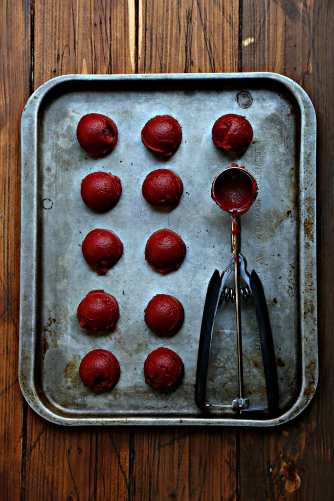 11 scoops of tomato paste on baking sheet with cookie scoop.