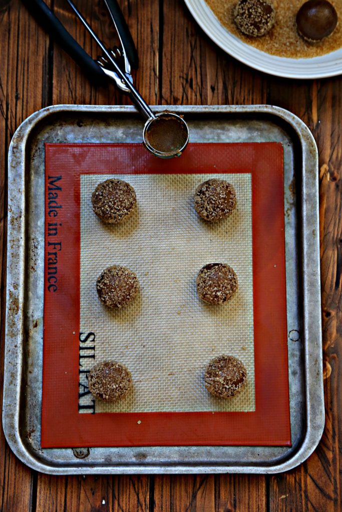 cookie balls on baking sheet. Cookie scoop visible.