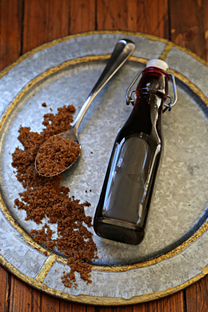 bottle of brown sugar simple syrup on silver plate with scattered brown sugar. 