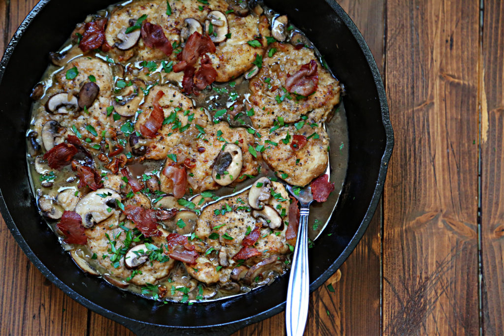 homemade chicken marsala recipe in cast iron skillet and brown wooden background