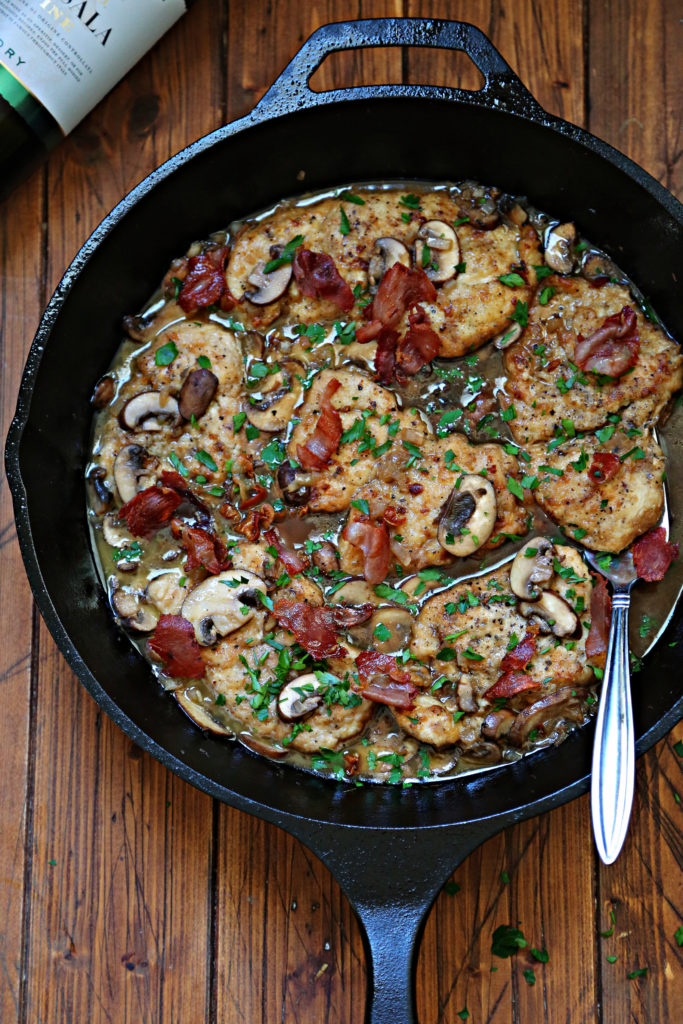homemade chicken marsala recipe in cast iron skillet and brown wooden background