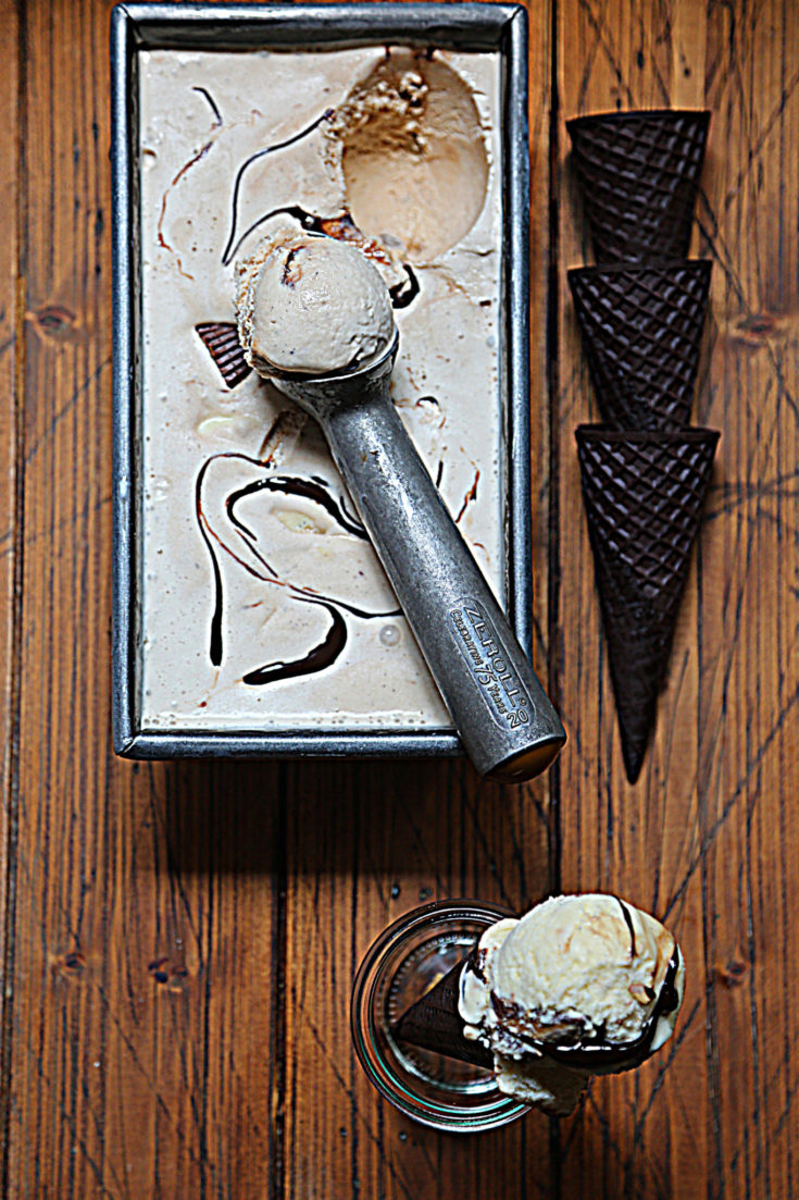 loaf pan with moose tracks ice cream and scooper. 3 chocolate cones to right of pan. Glass jar with cone standing in front of pan.