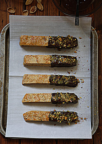 5 chocolate dipped biscotti sitting on baking sheet with parchment paper