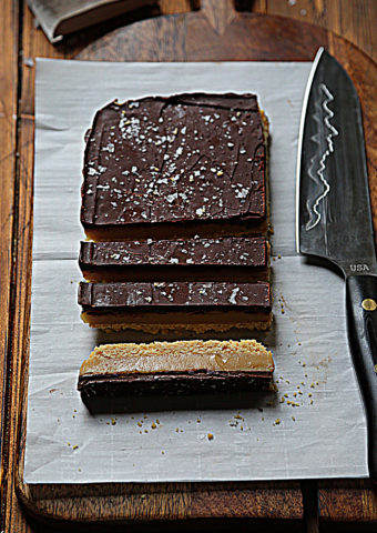 sliced millionaire's shortbread sitting on parchment paper, knife to side.