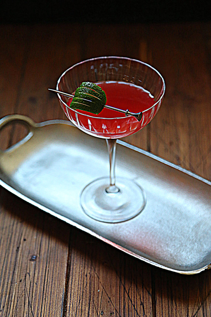 silver tray with scofflaw cocktail in coupe glass with lime garnish.