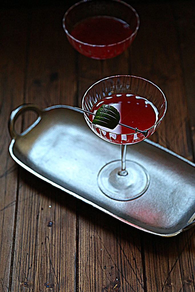 silver tray with scofflaw cocktail in couple glass with lime garnish. 