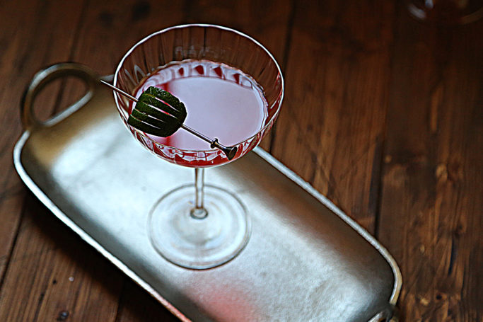 silver handled tray with scofflaw cocktail in coupe glass with lime garnish. 